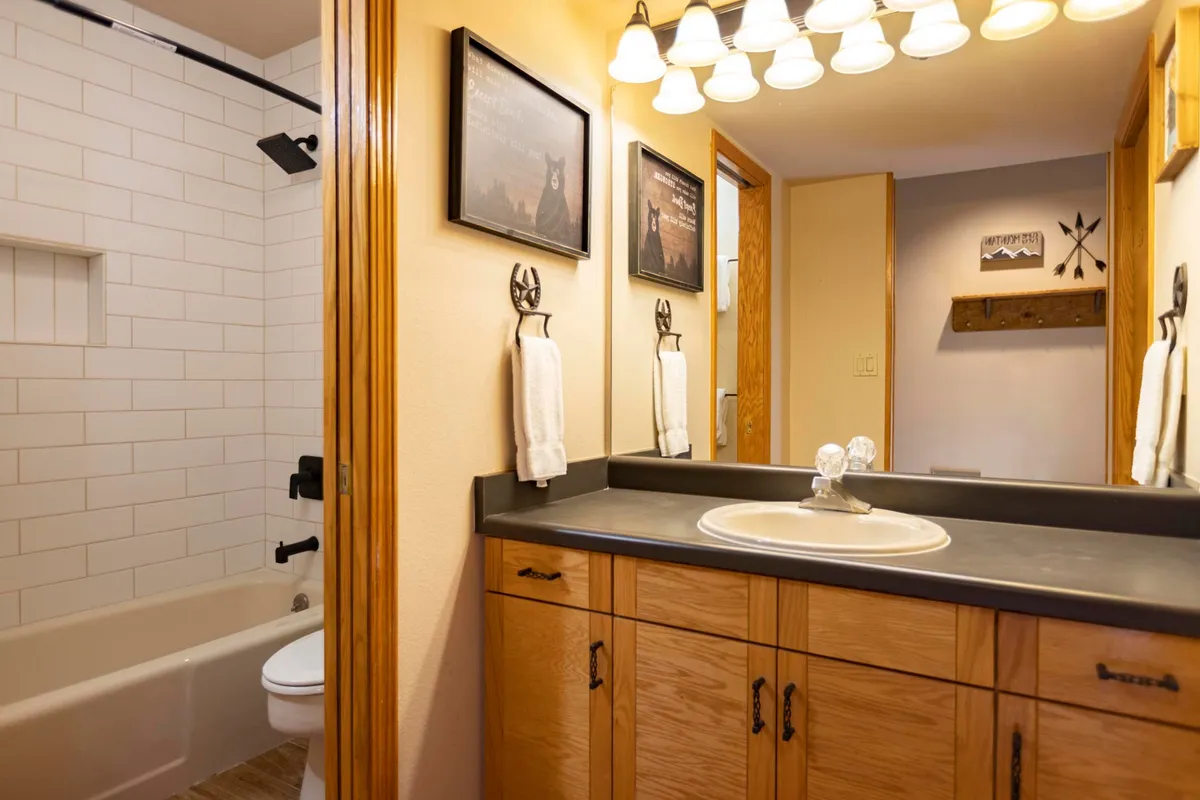 A functional yet warm bathroom vanity area, featuring a well-lit sink, framed artwork, and soft lighting fixtures that create an intimate atmosphere perfect for personal grooming and unwinding.
